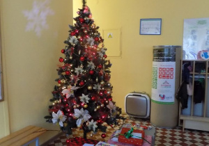Duże pudła z prezentami leżą przy choince w holu przedszkolnym.