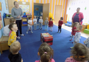 Dzieci z grupy krasnali stoją w kole i śpiewają piosenkę dla Mikołaja.