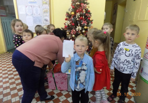 Chłopiec pokazuje list od Świętego Mikołaja- nauczycielka rozpakowuje pudło ozdobne.
