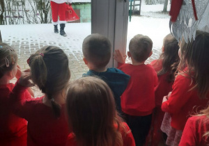Dzieci wygladaja przez okno na Świętego Mikołaja