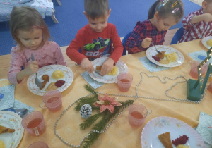 Dzieci jedzą uroczysty obiad wigilijny w klasie.