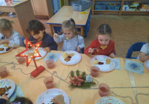Dzieci jedzą uroczysty obiad wigilijny w klasie.