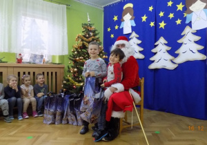 Święty Mikołaj rozdaje paczki świąteczne dzieciom z grupy III