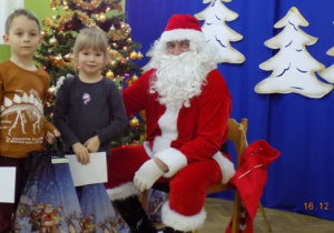 Święty Mikołaj rozdaje paczki świąteczne dzieciom z grupy IV