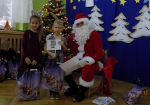 Święty Mikołaj rozdaje paczki świąteczne dzieciom z grupy IV