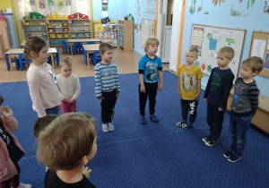 Dzieci stoją w kole na baczność i słuchają Hymnu Polski