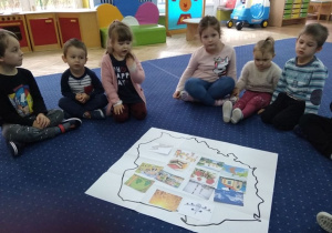 Dzieci siedzą w kole przy mapie Polski