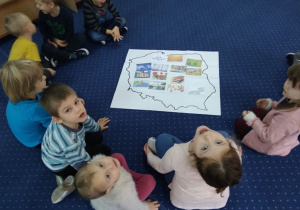 Dzieci siedzą w kole i oglądają mapę Polski