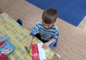 Chłopiec maluje farbami flagę Polski