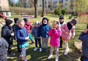 Dzieci szukają prezentu od zajączka wielkanocnego ukrytego w ogrodzie przedszkolnym