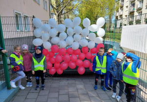 Dzieci na tle biało- czerwonej dekoracji z balonów
