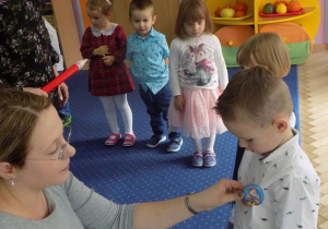 Nauczyciel przypina odznakę przedszkolaka dzieciom