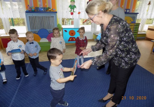 Dyrektor przedszkola rozdaje dyplomy przedszkolaka dzieciom