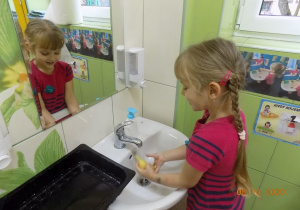 Dziewczynka myje owoce w umywalce.