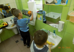 Chłopcy myją owoce i wycierają je w papierowy ręcznik.