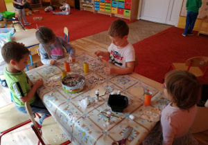 Dzieci wykonują pracę plastyczną przy stole.