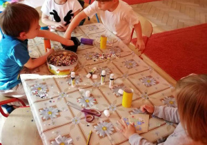 Dzieci wykonują pracę plastyczną przy stole.