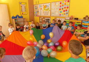 Dzieci tańczą z kolorowymi balonami i chustą animacyjną.