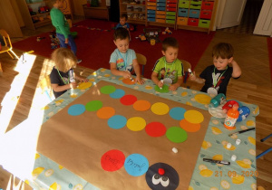 Dzieci smarują klejem kolorowe koła z papieru.