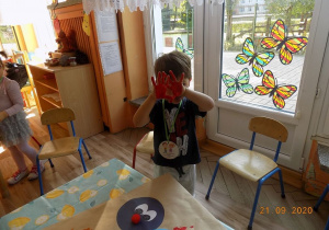 Chłopiec pokazuje dłonie pomalowane farbami.