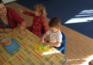 Dzieci wykonują pracę plastyczną- stemplowanie gąbką misia