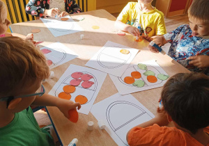 Dzieci liczą papierowe warzywa i owoce