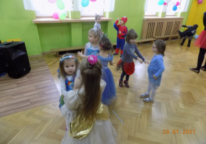 Dzieci w strojach karnawałowych tańczą na sali gimnstaycznej.