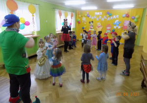 Dzieci z nauczycielkami i panem prowadzącym tańczą i śpiewają do piosenki Kaczuszki.
