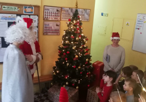 Dzieci, Mikołaj i nauczycielka stoją przy choince