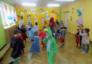 Dzieci z grupy skrzatów, przebrane za postacie z bajek tańczą na sali gimnastycznej.