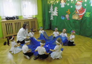 Dzieci przebrane za gwiazdki siedzą przy niebieskiej chuście