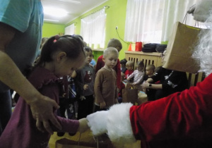 Dziecko z grupy II otrzymuje paczkę świąteczną od Mikołaja