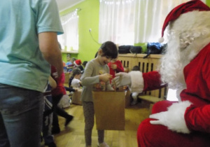 Dziecko z grupy II otrzymuje paczkę świąteczną od Mikołaja