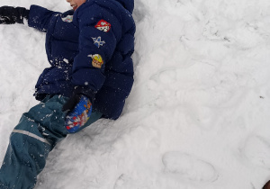 Chłopiec leży na śniegu