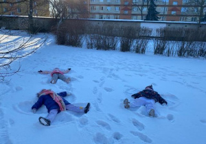 Dzieci wykonują aniołki na śniegu