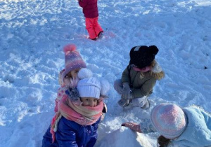 Dzieci tworzą bałwanka ze śniegu