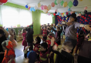 Dzieci w strojach karnawałowych tańczą w rytm muzyki.