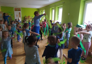 Dzieci tańczą z zielonymi szarfami.