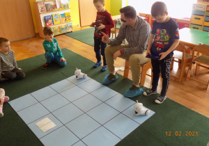 Dzieci uczestniczą w zajęciach z kodowania z wykorzystaniem maty kodującej i robota Photon