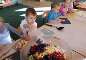 Dzieci wykonują sałatkę owocową, samodzielnie kroją owoce