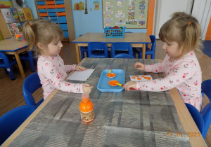 Dzieci wykonują kleksy pomarańczowe na kartce papieru