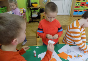 Dzieci z grupy elfów wykonuja pracę plastyczną wyklejankę.