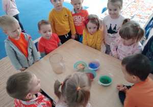 Dzieci z grupy I oglądają eksperyment- barwienie wody bibułą