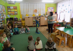 Dzieci z grupy trzeciej obserwują eksperyment z balonem, który pokazuje nauczycielka.