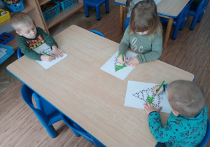 Dzieci z grupy I kolorują na zielono choinkę