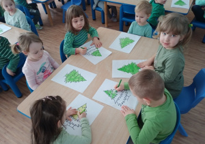 Dzieci z grupy I kolorują na zielono choinkę