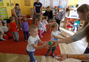 Dzieci z grupy drugiej celują piłeczkami do bramek zrobionych z rąk rodziców