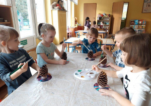 Dzieci malują farbami szyszki