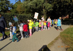 Dzieci w równym rzędzie idą parami ścieżką na polu