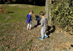 Dzieci zbierają patyki na placu zabaw.